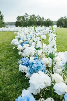 Ongelooflijk mooie buitenceremonie op groen gras en houten stoelen en trouwdag met verse bloemen