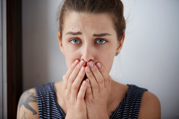 Gratis foto ongelukkig overweldigd meisje met hoofdpijn, slechte dag houdt handen op gezicht