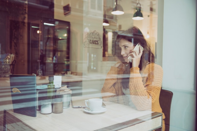 Ongelukkige vrouw die op telefoon in koffie spreekt