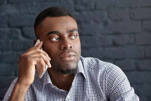 Ongerust gemaakte jonge Afrikaanse zakenman die op mobiele telefoon spreekt