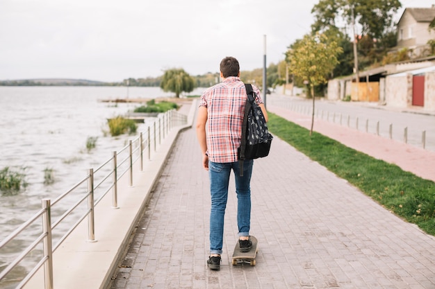 Onherkenbaar tiener berijdend skateboard dichtbij water