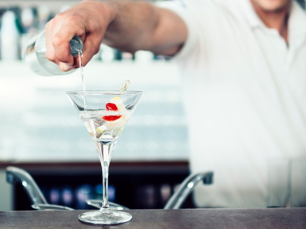 Gratis foto onherkenbare barman gieten cocktail in glas