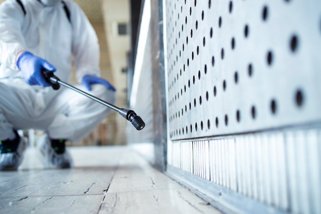 Gratis foto onherkenbare persoon in wit chemisch beschermingspak die openbare ruimtes desinfecteert om de verspreiding van het zeer besmettelijke coronavirus te stoppen