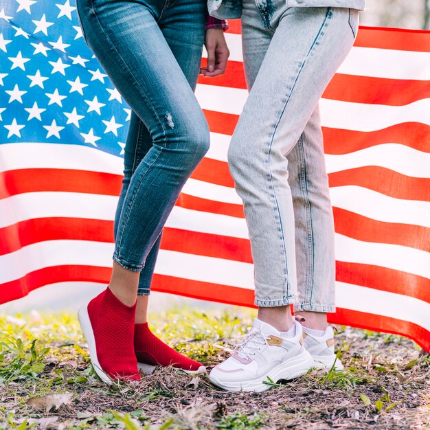 Onherkenbare vrouwen die zich op grond bevinden en vlag van de VS erachter houden