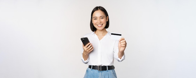 Online winkelconcept dat een modern aziatisch meisje glimlacht, laat zien dat haar creditcard een mobiele telefoonbestelling heeft