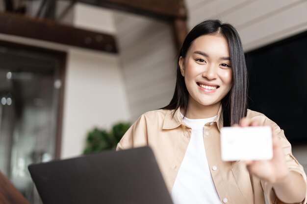 Online winkelen jonge vrouw betalen voor aankoop met creditcard kopen op websites op laptop sittin...