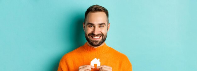 Onroerend goed concept gelukkige jonge man op zoek naar huis huur houden huis papier maket en lachende st