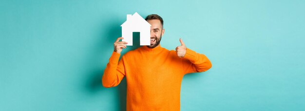 Onroerend goed concept tevreden man die bureau aanbeveelt met duim omhoog en huismaket die overeind staat