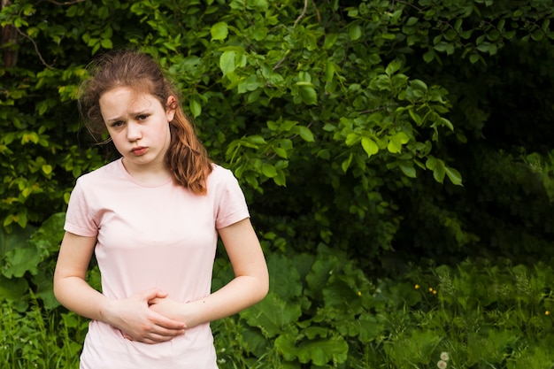 Onschuldig meisje houdt haar buik vast terwijl ze buikpijn heeft in het park