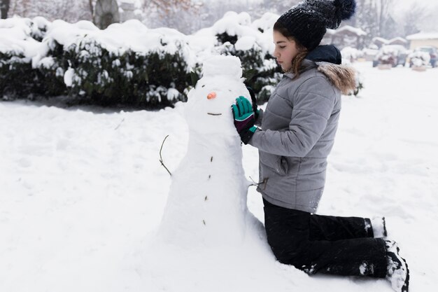 Onschuldig meisje wat betreft sneeuwman in de winter