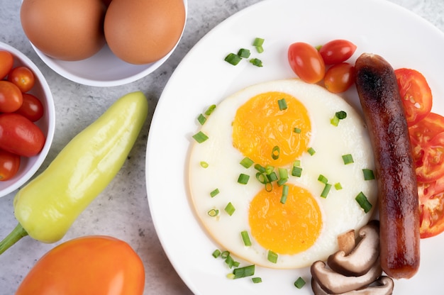 Ontbijt bestaande uit brood, gebakken eieren, tomaten, Chinese worst en champignons.