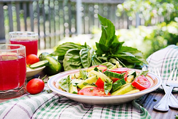 Ontbijt in de zomertuin. Salade van tomaten en komkommers met groene uien en basilicum.