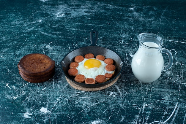 Ontbijtbord met gebakken eieren, worst en pannenkoeken.