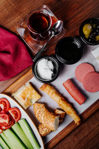 Ontbijtbord met gemengd voedsel, een glas zwarte thee en broodvariëteit.