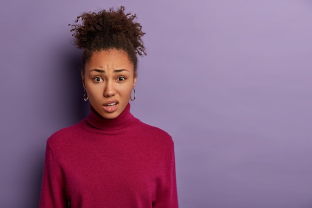 Ontevreden afro-vrouw grijnst het gezicht en tuit de lippen, reageert op het horen van iets onaangenaams