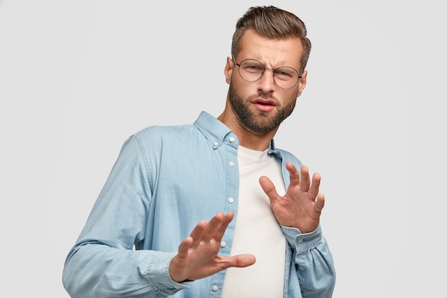 Ontevreden bebaarde man poseren tegen de witte muur