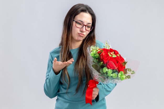 Ontevreden jong meisje op Valentijnsdag bedrijf en wijst met de hand op boeket geïsoleerd op een witte achtergrond