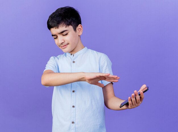 Ontevreden jonge blanke jongen die mobiele telefoon houdt die geen gebaar met hand met gesloten ogen doet geïsoleerd op paarse achtergrond met kopie ruimte