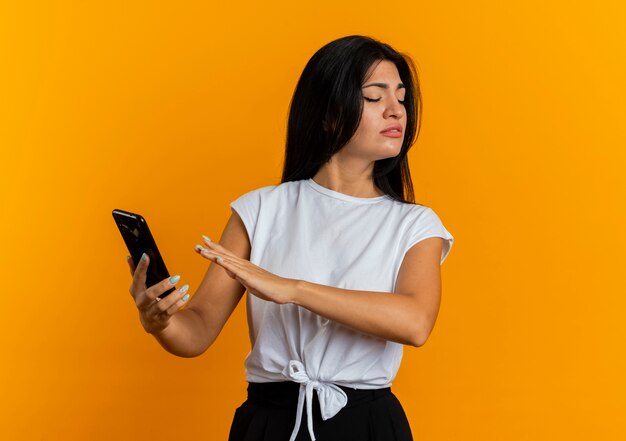 Ontevreden jonge blanke vrouw houdt het telefoonscherm met de hand vast en kijkt naar de zijkant