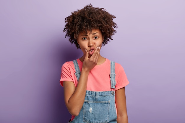 Ontevreden mooie jonge vrouw met een afro poseren in overall