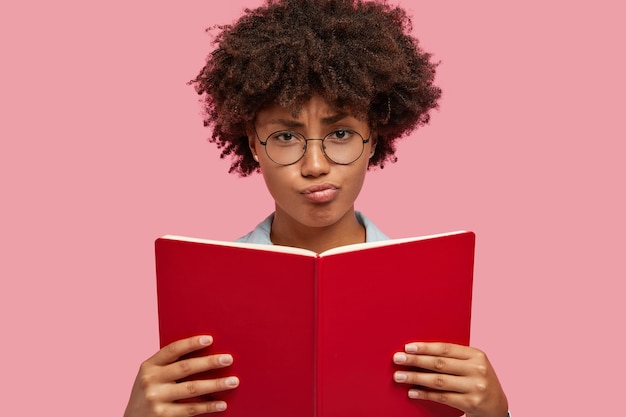 Ontevreden mooie vrouw poseren tegen de roze muur