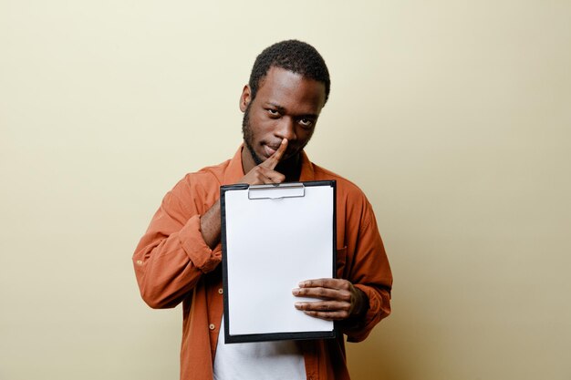 Ontevreden tonen stilte gebaar jonge Afro-Amerikaanse man met klembord geïsoleerd op een witte achtergrond