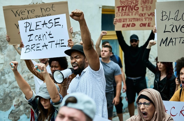 Ontevreden zwarte man met opgeheven vuist schreeuwt door megafoon terwijl hij Black Lives Matter-demonstraties leidt op straat