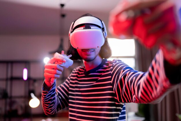 Ontspan Aziatische volwassen man met Virtual Reality-headset en met controllers speelt in een bokssport Videogame thuis Speel VR actieve sportgame online in de woonkamer met rgb-verlichtingsstemming