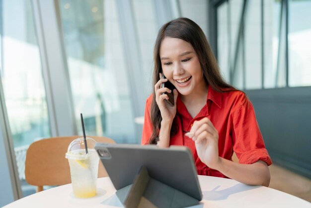 Ontspan vrije tijd aantrekkelijke slimme aziatische vrouwelijke freelance ondernemer glimlach en geniet van het werken met smartphone en laptop in café met vervagen stad zakelijke digitale nomade casual ideeën concept