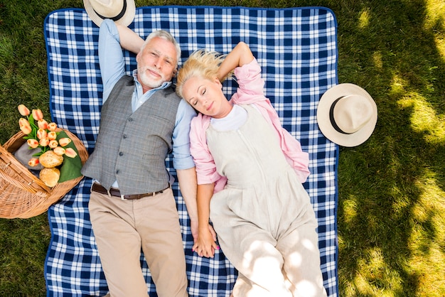 Ontspannen bejaard paar die op het gras leggen