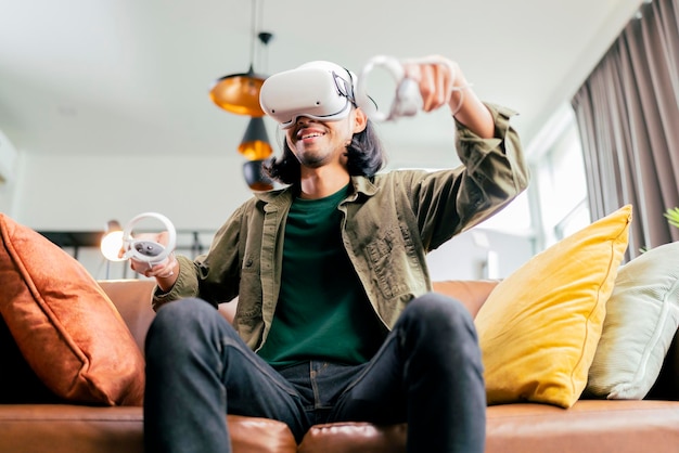 Ontspannen casual aziatische volwassen man met virtual reality-headset en met controllers speelt in een sport videogame thuis vr actieve sportgame online spelen in de woonkamer