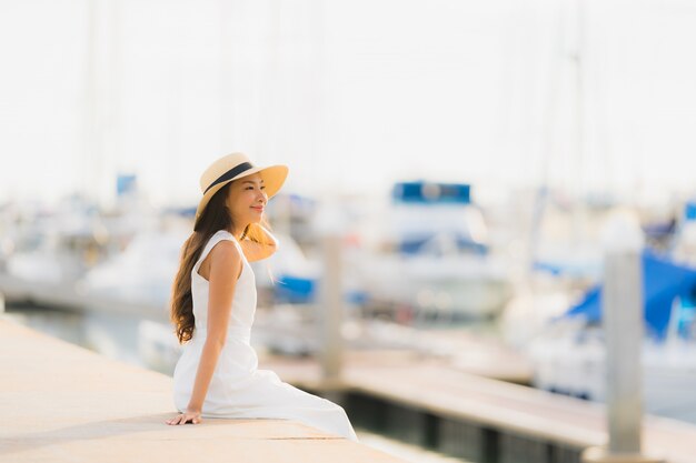 Ontspannen de gelukkige jonge Aziatische vrouw van de vrouwenvrije tijd ontspant rond jachthaven