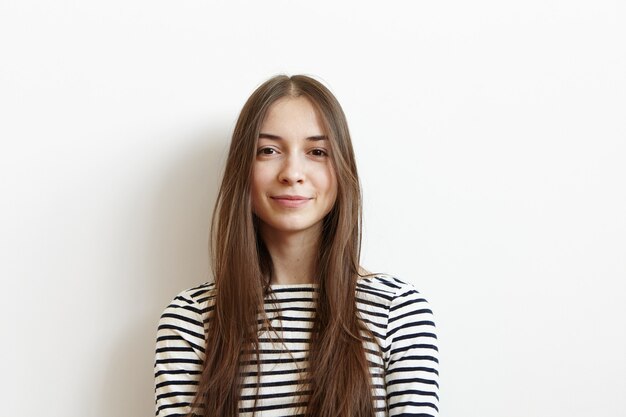 Ontspannen en zorgeloze jonge blanke vrouw die haar lange haren los glimlachend vreugdevol draagt