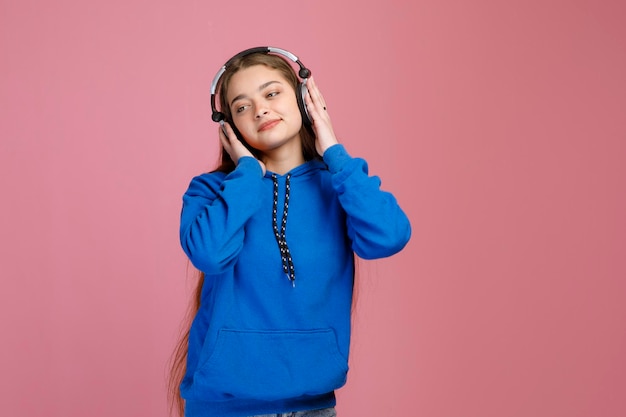 Ontspannen knappe meisje die koptelefoon op haar oor drukt terwijl ze naar muziek luistert.