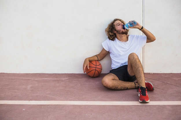 Ontspannen man met basketbal drinkwater