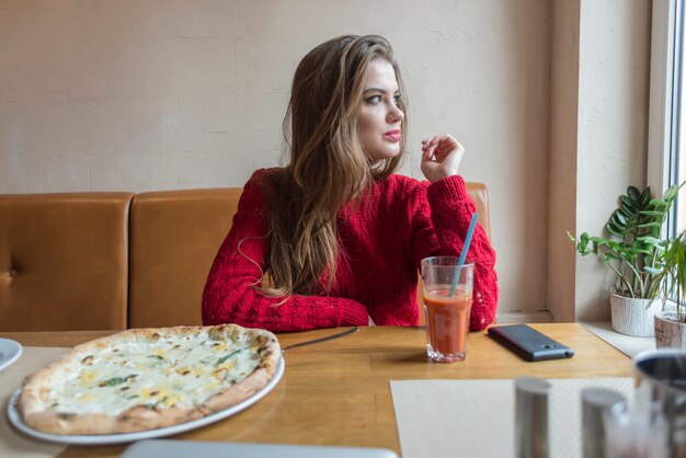 Ontspannen meisje kijkt door het raam in een restaurant