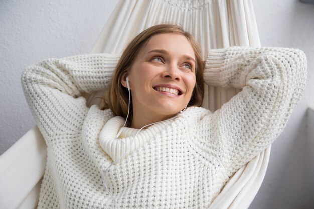 Ontspannen vrouw die aan muziek in oortelefoons luistert