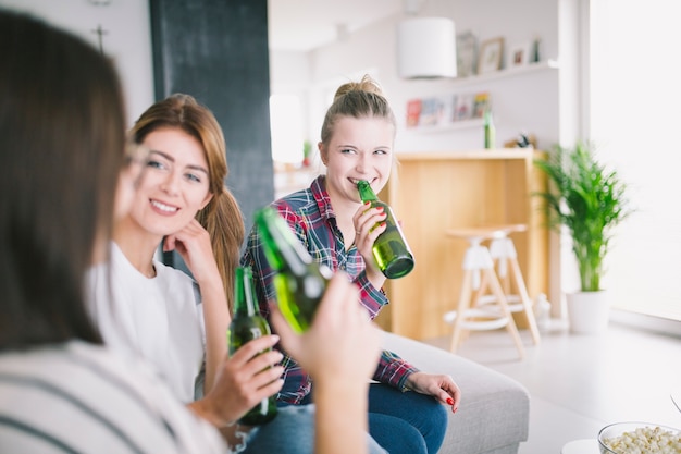 Ontspannende jonge vrouwen die bier thuis drinken