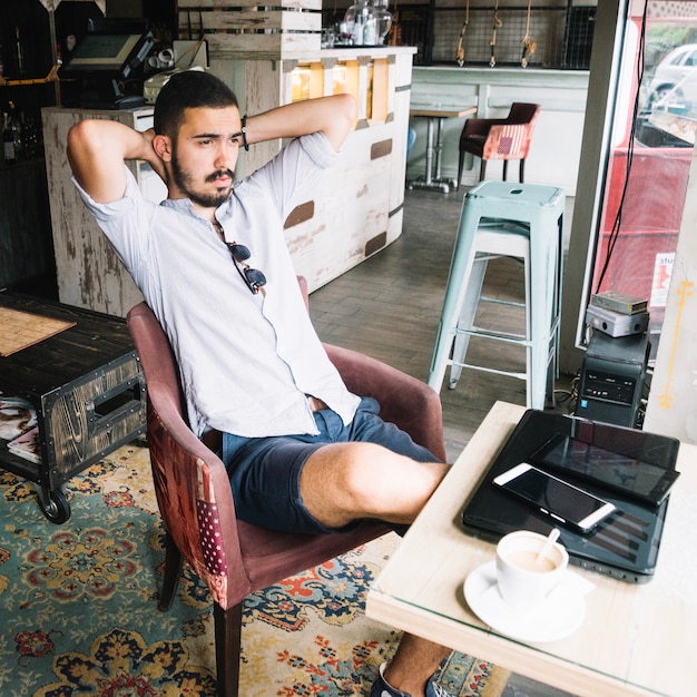 Ontspannende man poseren in stoel in cafe