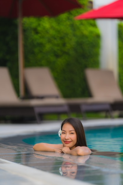Ontspant de portret jonge Aziatische vrouw glimlach gelukkig rond openluchtzwembad in hoteltoevlucht met overzeese oceaanmening