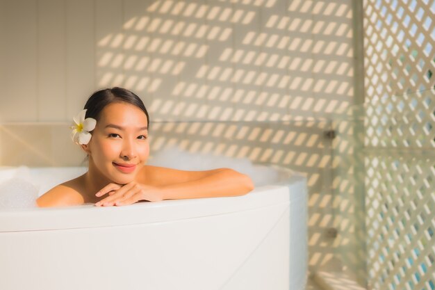 Ontspant de portret jonge Aziatische vrouw neemt een bad in badkuip