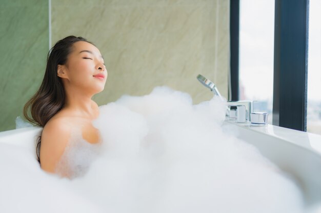 Ontspant de portret mooie jonge Aziatische vrouw en vrije tijd in badkuip