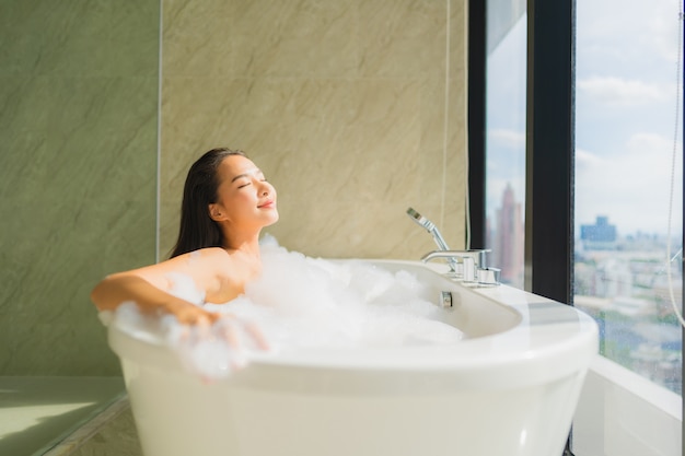 Ontspant de portret mooie jonge Aziatische vrouw en vrije tijd in badkuip