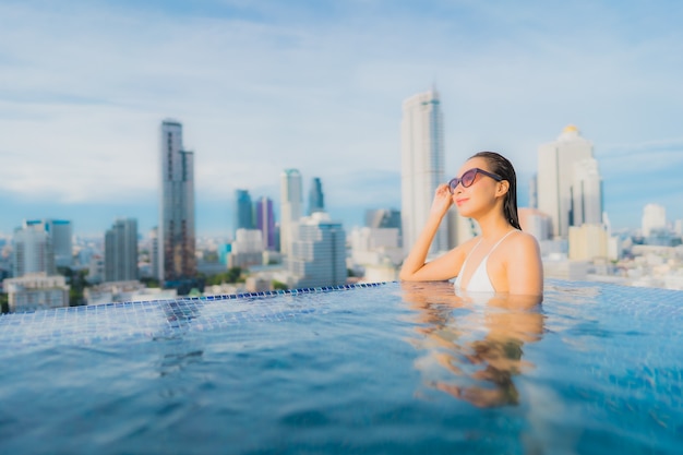 Ontspant de portret mooie jonge Aziatische vrouw gelukkige glimlachvrije tijd rond openluchtzwembad