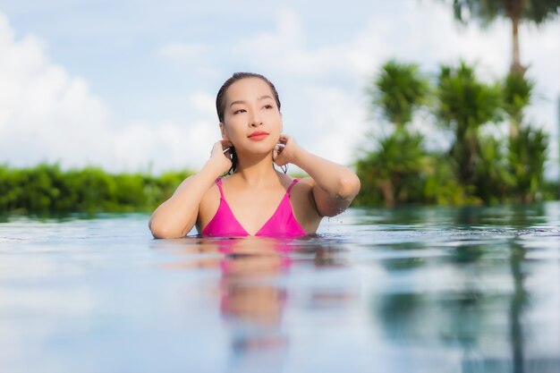 Ontspant de portret mooie jonge aziatische vrouw geniet rond openluchtzwembad in vakantievakantie