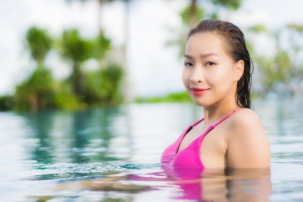 Ontspant de portret mooie jonge aziatische vrouw geniet rond openluchtzwembad in vakantievakantie