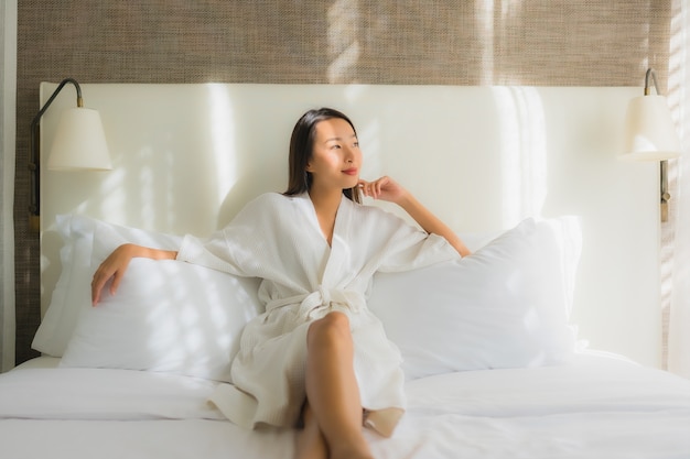 Ontspant de portret mooie jonge Aziatische vrouw glimlach op bed in slaapkamer