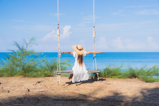 Ontspant de portret mooie jonge aziatische vrouw glimlach op schommeling rond strand overzeese oceaan voor aardreis in vakantie