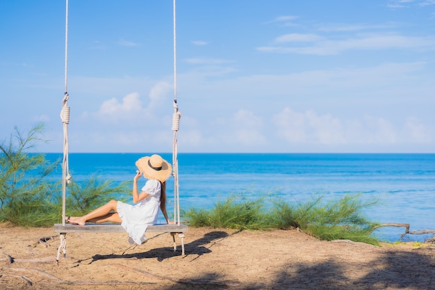 Ontspant de portret mooie jonge aziatische vrouw glimlach op schommeling rond strand overzeese oceaan voor aardreis in vakantie