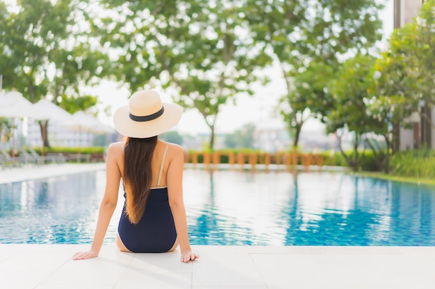 Ontspant de portret mooie jonge aziatische vrouw glimlach rond openluchtzwembad in hoteltoevlucht op vakantiereizen